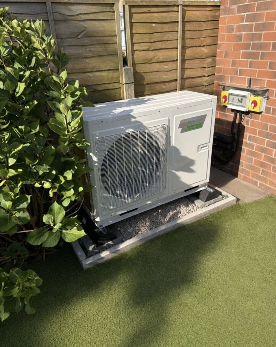 Air source heat pump on a raised gravel base in a back garden