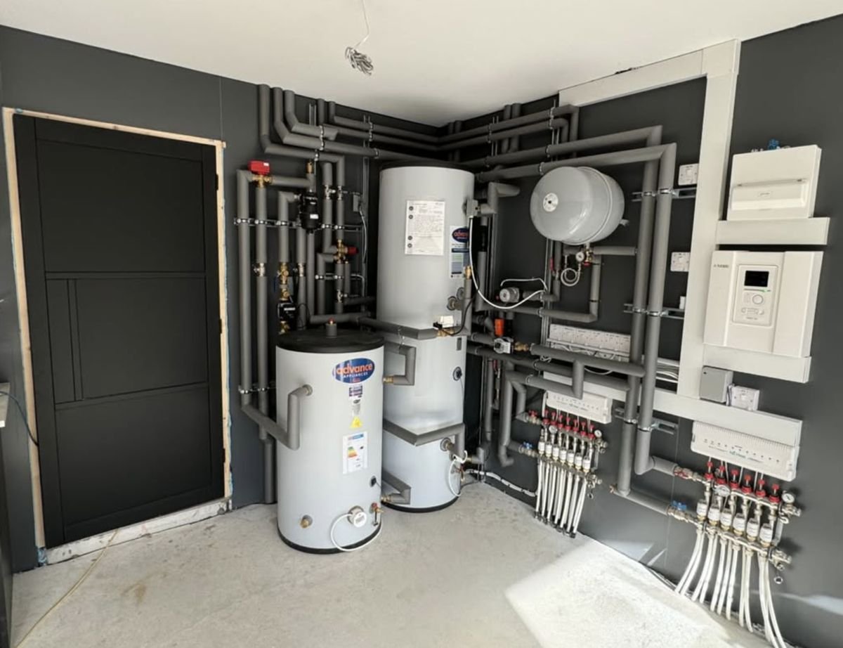 Heat pump plant room with hot water cylinders, expansion vessel and underfloor heating manifolds