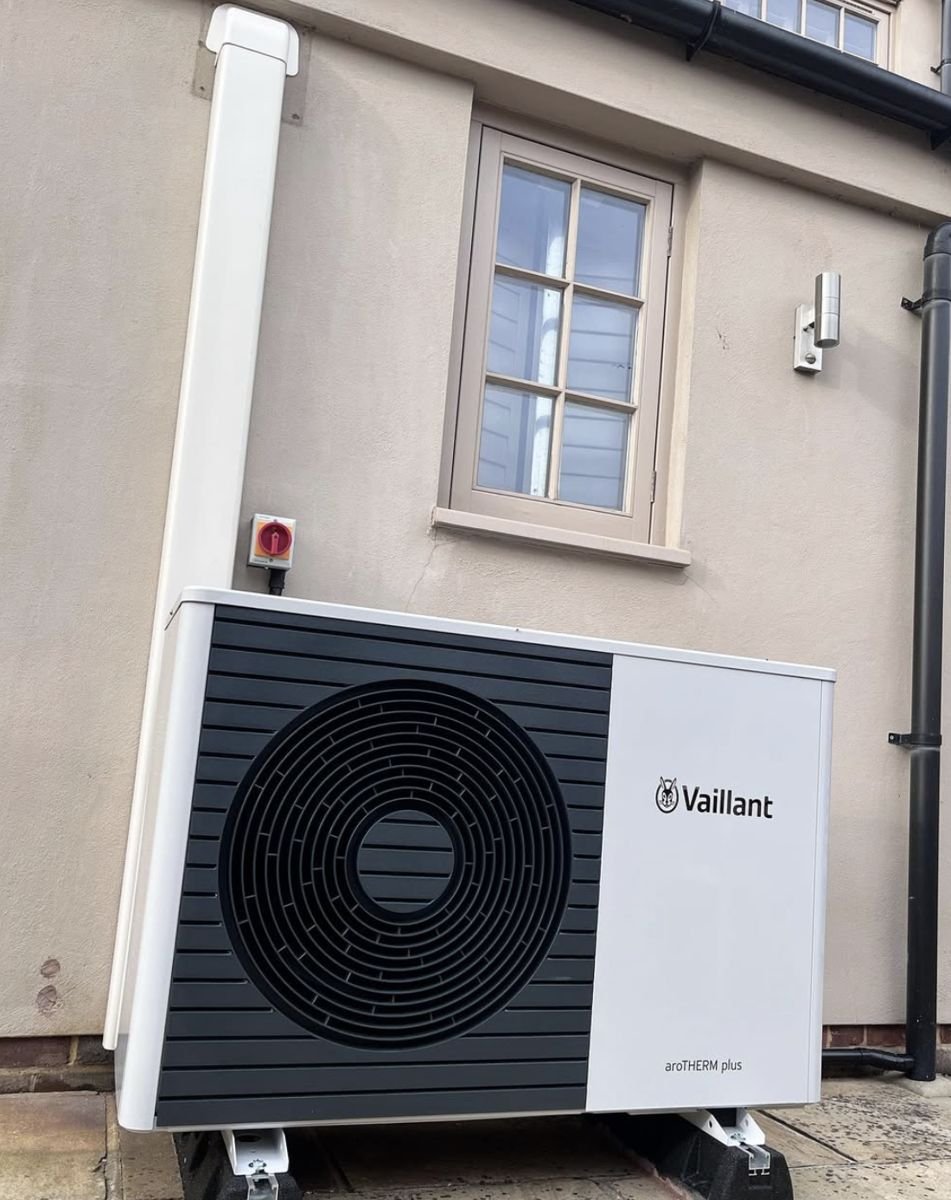 White Vaillant aroTHERM plus heat pump against a rendered house wall